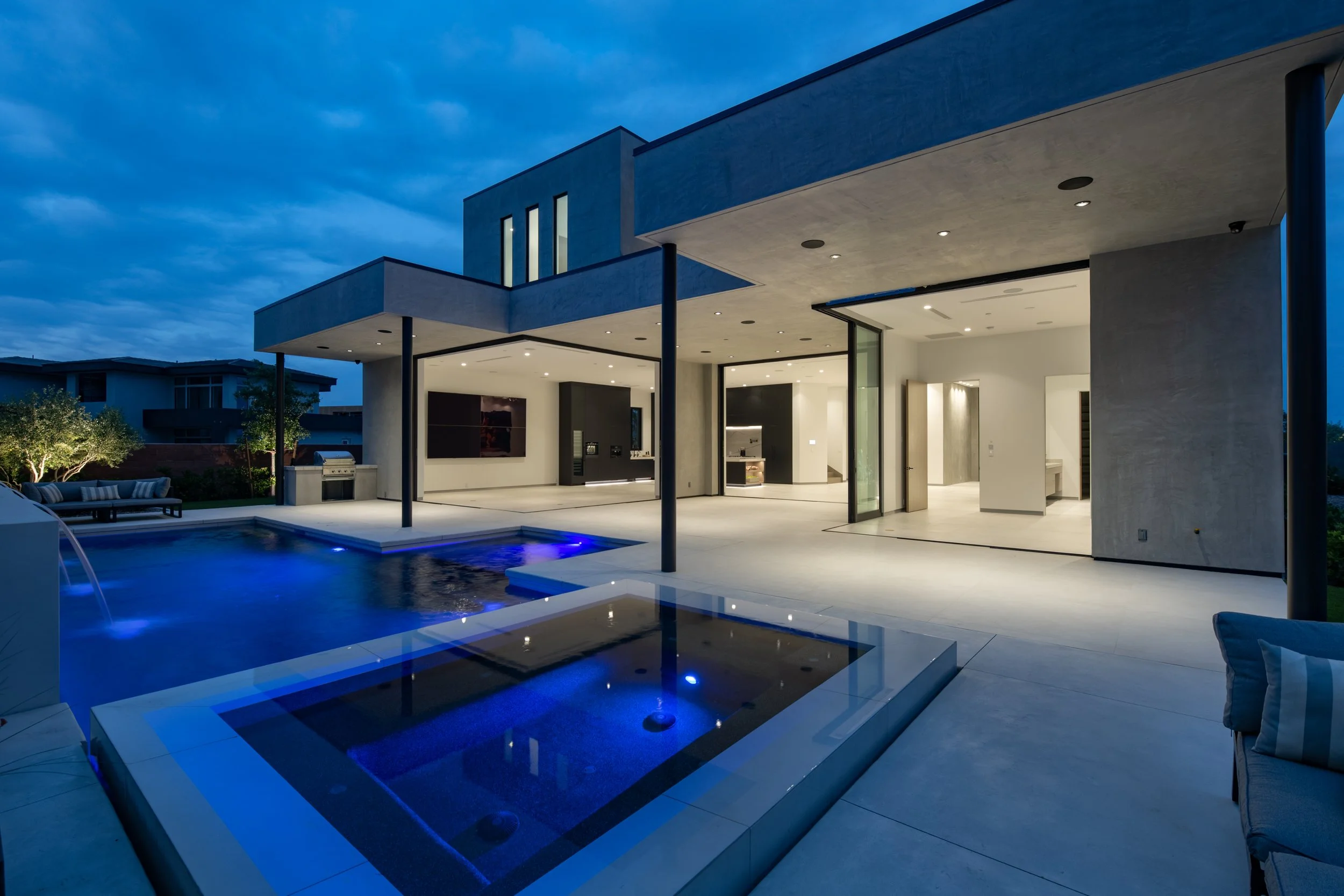 A modern Manner Builders custom home at dusk with an illuminated pool